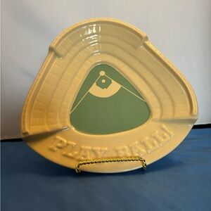 A triangular stadium shaped dish with a tan exterior and green painted in field.